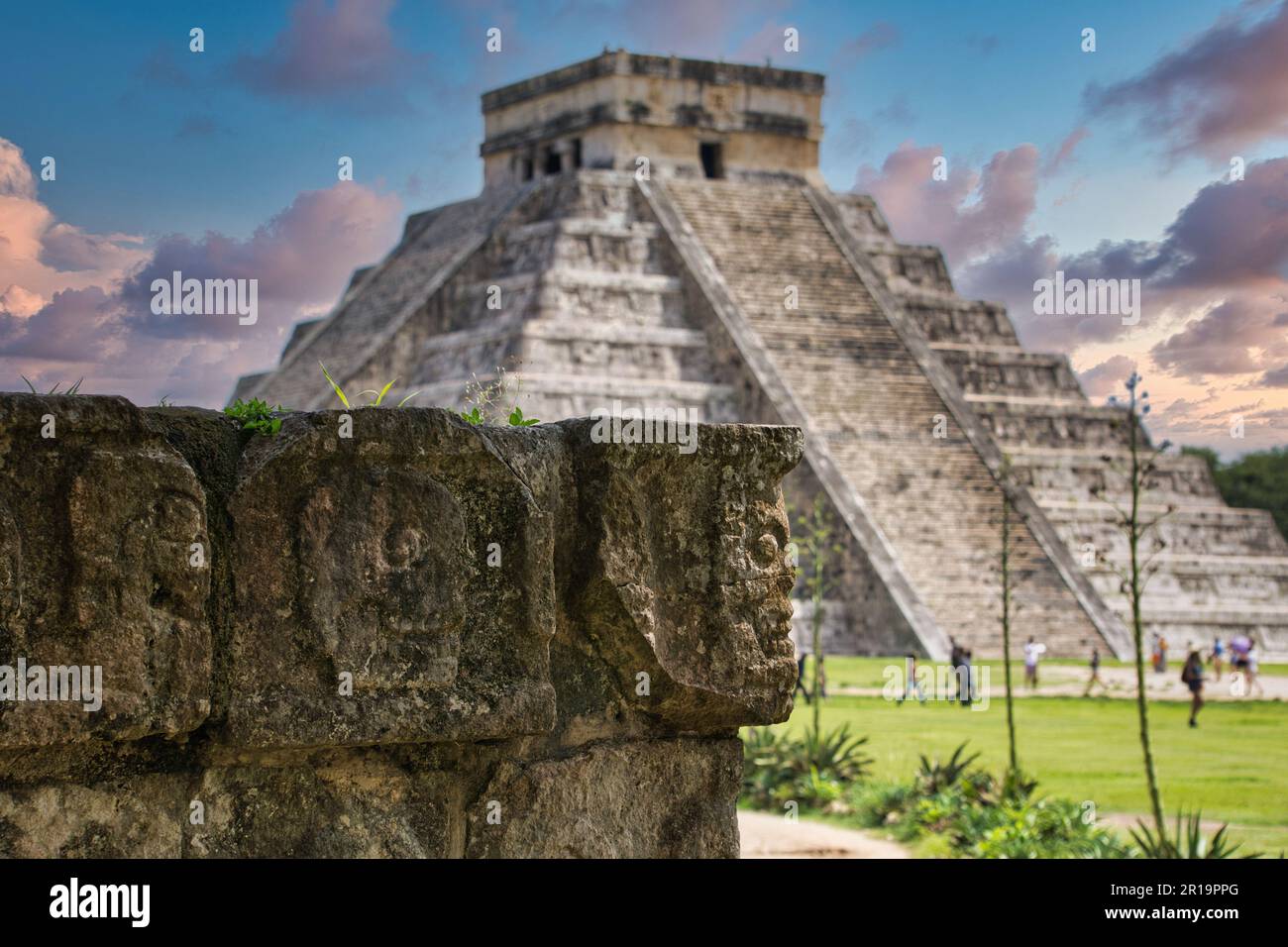 Teschi Maya con lo sfondo della piramide Chichen Itza e turisti a piedi. Foto Stock