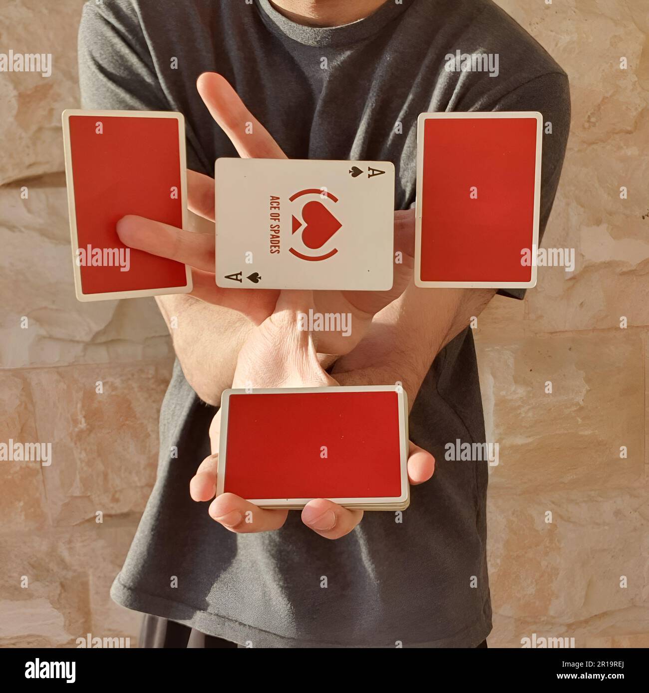 Un giovane che esegue un trucco di carta con un mazzo di carte rosse da gioco. Foto Stock