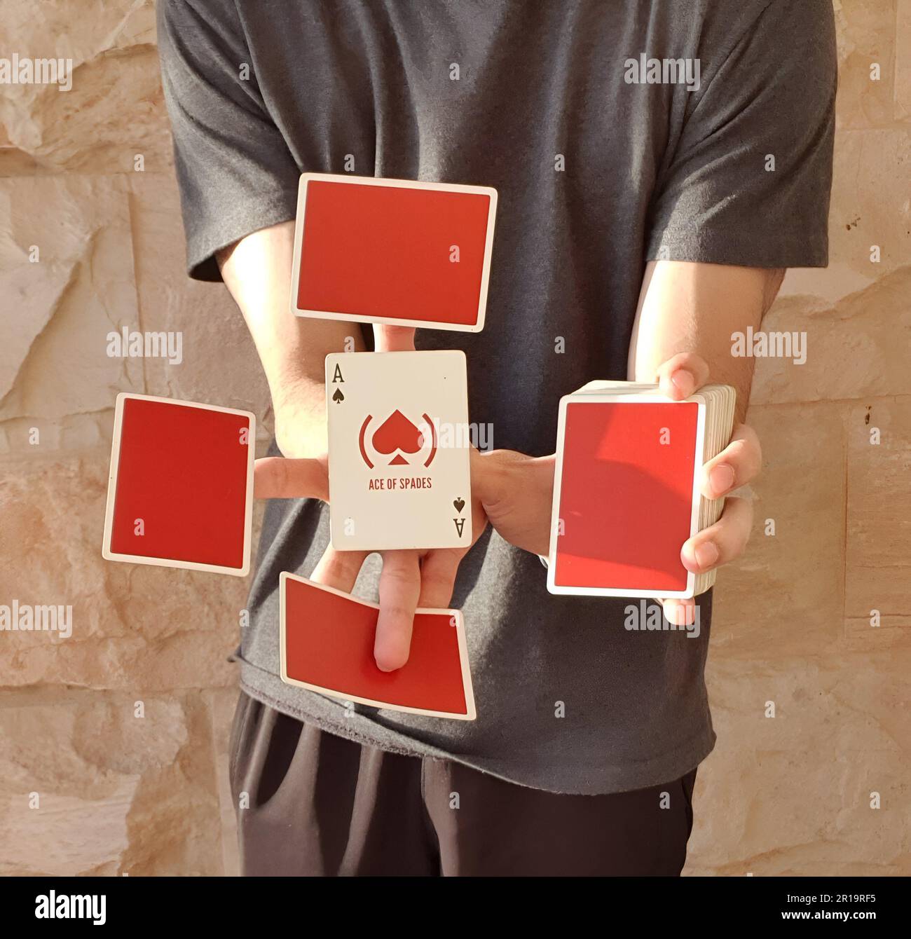 Un giovane che esegue un trucco di carta con un mazzo di carte rosse da gioco. Foto Stock