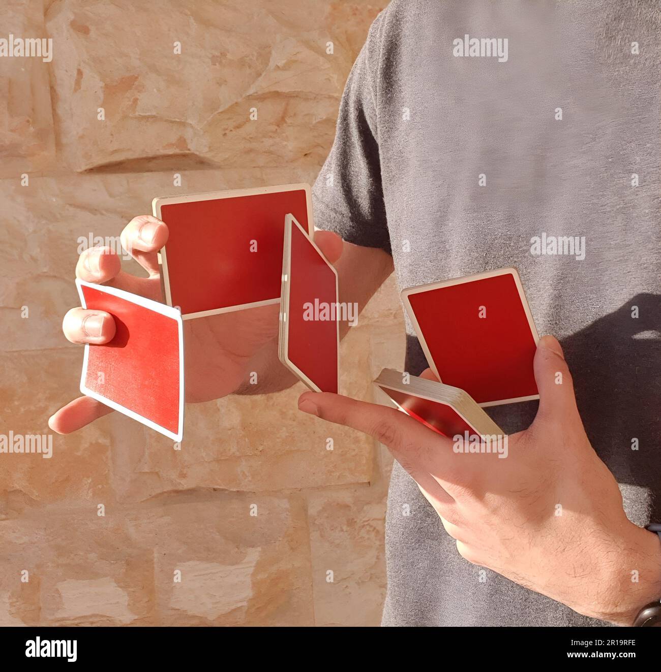Un giovane che esegue un trucco di carta con un mazzo di carte rosse da gioco. Foto Stock