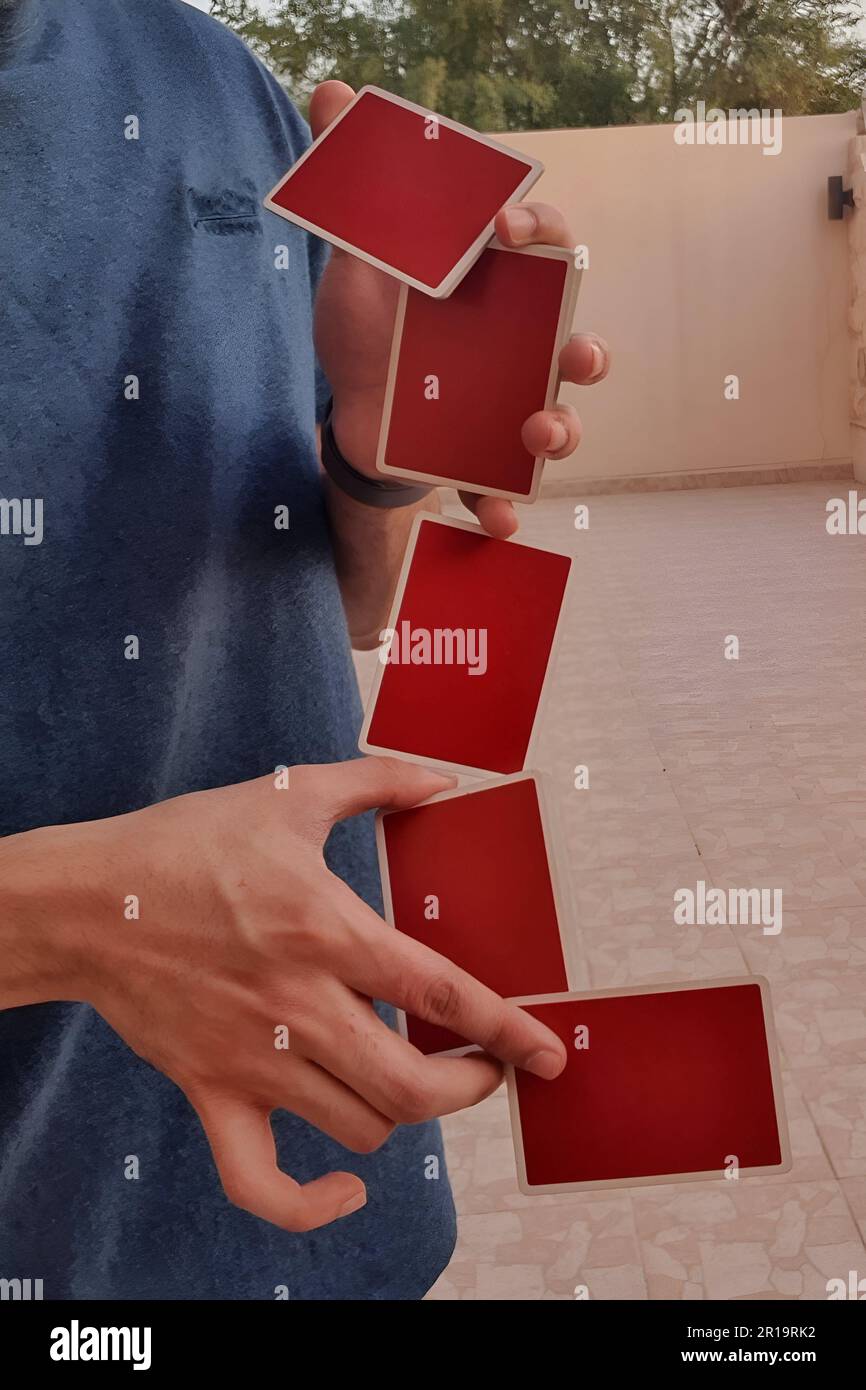 Un giovane che esegue un trucco di carta con un mazzo di carte rosse da gioco. Foto Stock