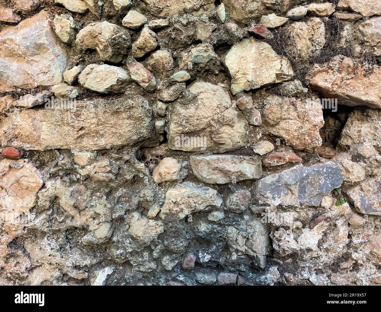 Sfondo, texture, muro di pietra di pietre rotonde ciottoli mattoni superficie naturale naturale affilato convesso ruvido pietra di ciottoli con crepe. Foto Stock
