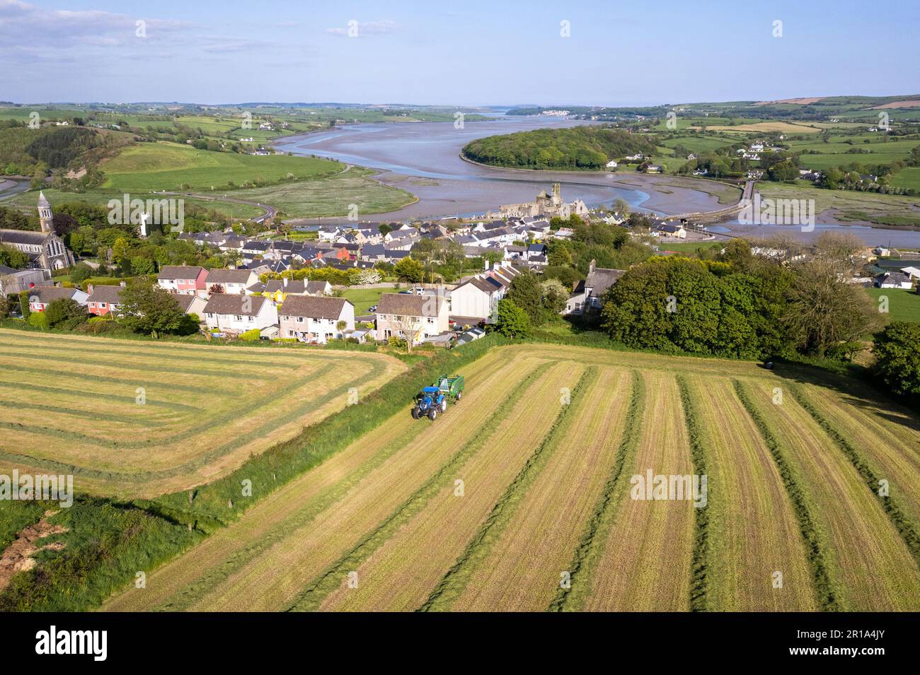 Timoleague, West Cork, Irlanda. 12th maggio, 2023. Barry Long di Eoin Coomey Agri & Plant LTD, balle di erba per l'agricoltore di Timoleague John Michael Foley che utilizza un trattore New Holland T7,245 e una pressa McHale Fusion 3 Plus. Il villaggio costiero di Timoleague e il suo estuario è raffigurato sullo sfondo. Credit: AG News/Alamy Live News Foto Stock