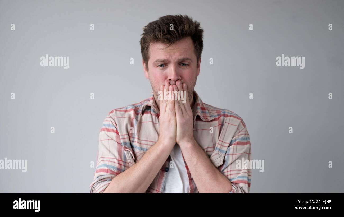 Il giovane europeo stanco, privo di energia, chiude il volto con le mani. Non ha emozioni positive Foto Stock