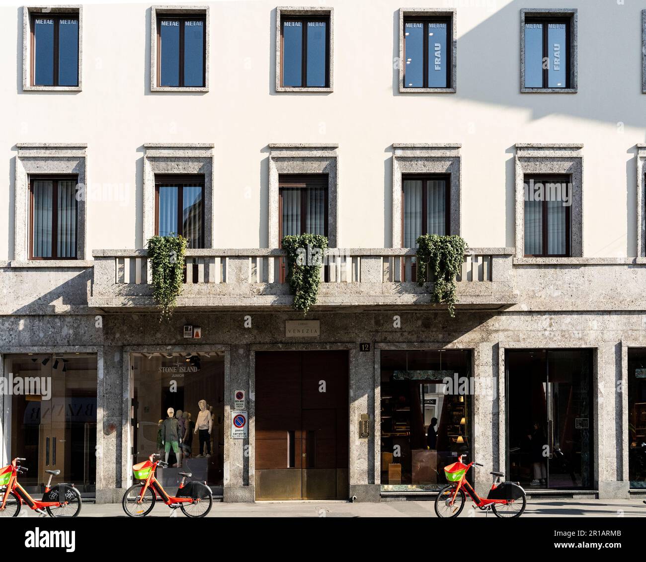 Un edificio e una boutique di moda in corso Venezia (Via Venezia), con tre biciclette a noleggio parcheggiate. Milano centro, Italia Foto Stock