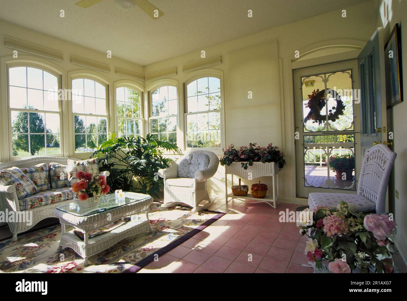 Accogliente veranda con mobili in vimini e sole che scorre dalle finestre Foto Stock