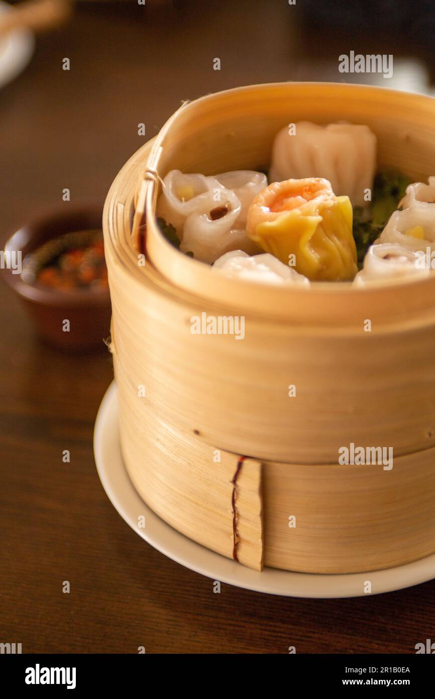 Dim Sum al vapore servito in un cestino di bambù Foto Stock