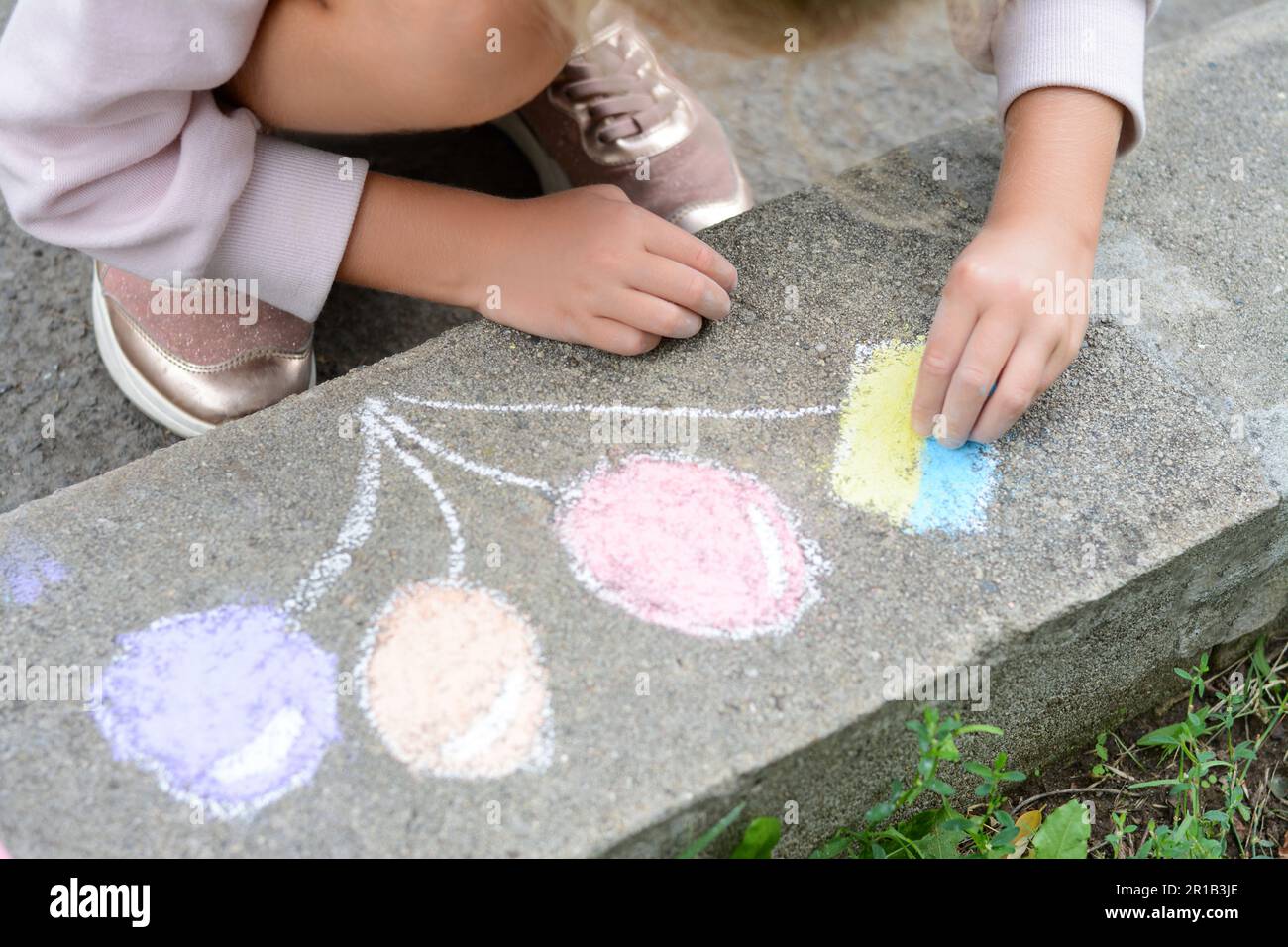 Bambino piccolo disegno palloncini e bandiera ucraina con gesso sul marciapiede all'aperto, primo piano Foto Stock