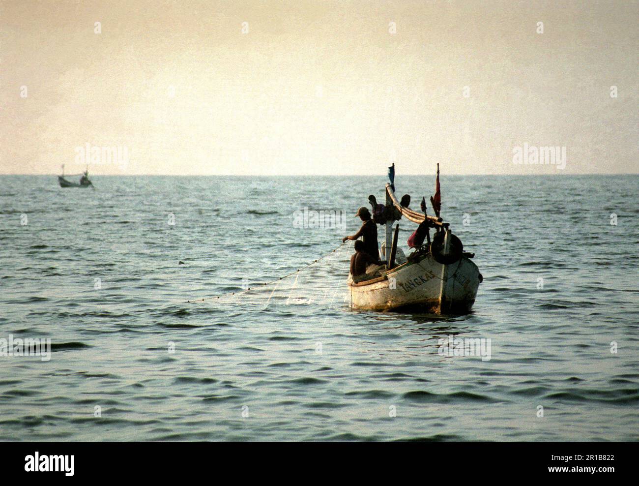 I pescatori lavorano da pescherecci sulle acque costiere di Giacarta, sullo sfondo della Baia di Giacarta; fotografati dalla spiaggia di Karnaval (Carnival) a Ancol Dreamland ad Ancol, Pademangan, Giacarta Nord, Giacarta, Indonesia. Foto Stock