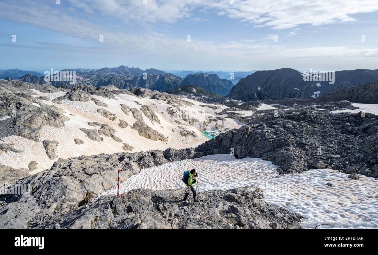 Alpinista che sale sul Hochkoenig, altopiano roccioso con resti di neve, Alpe di Uebergossene, vista sulle Steinerne Meer, Alpi Berchtesgaden Foto Stock