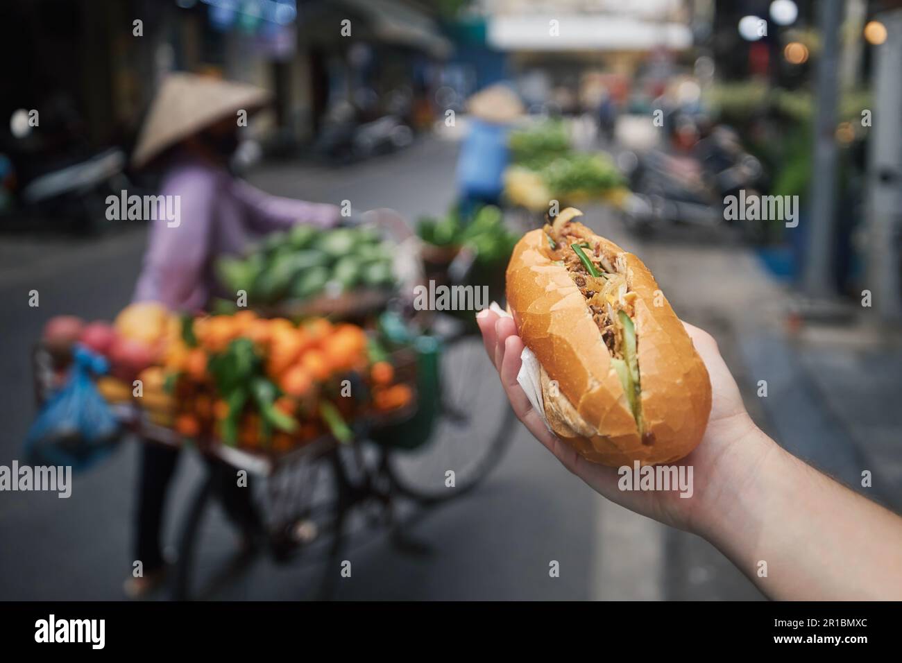 Cibo di strada ad Hanoi. Panino Banh mi tenuto a mano. Primo piano della tradizionale baguette vietnamita farcita di paté, carne e verdure. Foto Stock