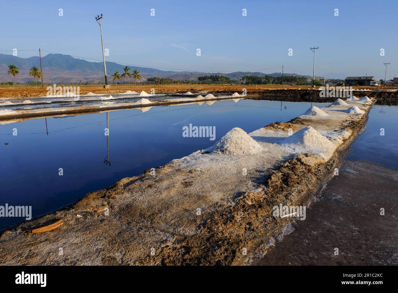 Il processo di cristallizzazione dell'acqua di mare in sale in modo tradizionale in Indonesia. Foto Stock