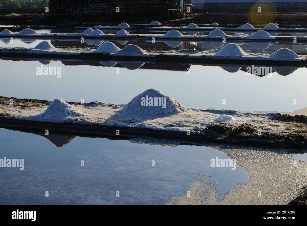 Il processo di cristallizzazione dell'acqua di mare in sale in modo tradizionale in Indonesia. Foto Stock