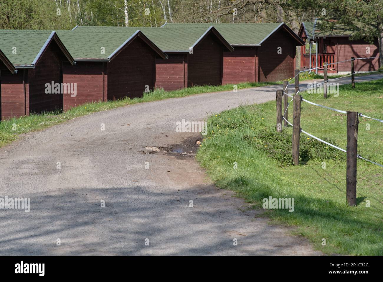Fila di case vacanze estive in legno lungo polverosa strada rurale nella campagna ceca. Affitto a buon mercato vacanza foresta alloggio cabina. Foto Stock
