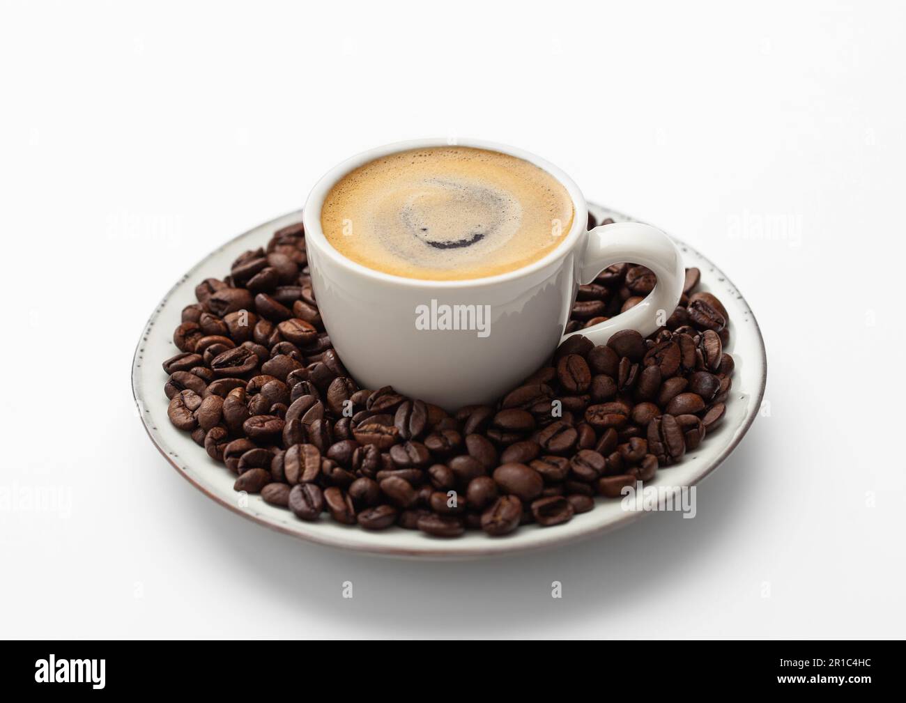 Caffè espresso in tazza piccola e chicchi freschi su piattino bianco. Foto Stock