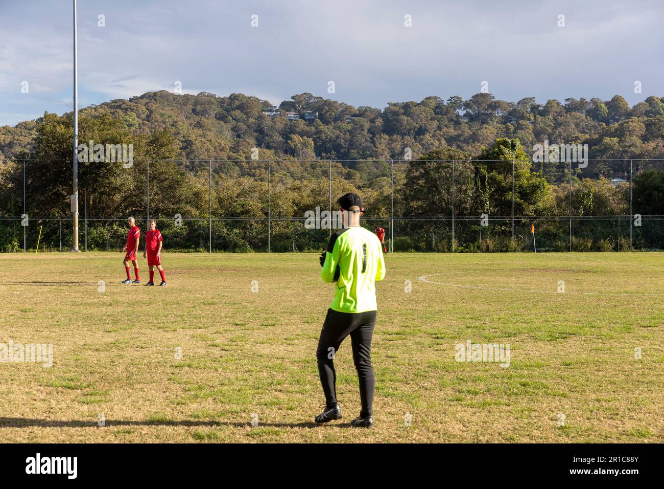 Portiere australiano e giocatori in striscia rossa riscaldano prima di gioco di calcio amatoriale per più di 45 a Sydney, NSW, Australia Foto Stock