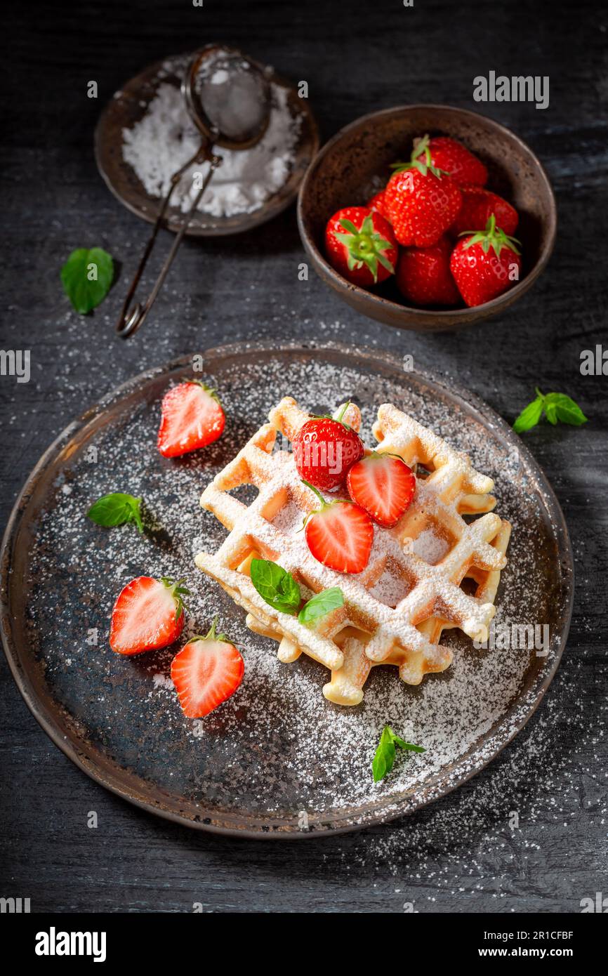 Wafer gustosi e dolci con fragole e menta. Cialde con fragole e zucchero a velo. Foto Stock
