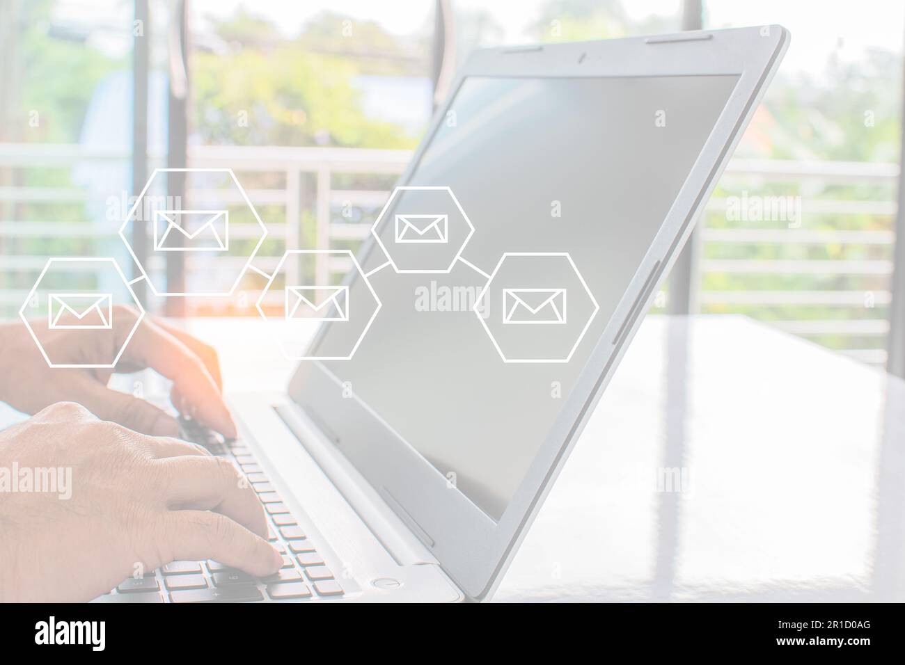 Mano di un uomo d'affari che digita sulla tastiera di un notebook per inviare via e-mail. Lo schermo del laptop è vuoto e sfocato. Il concetto di lavoro a casa e dista sociale Foto Stock