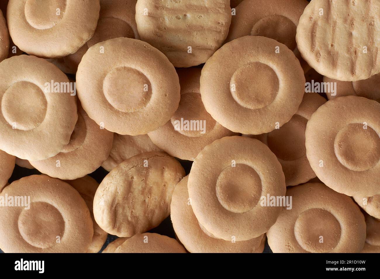 primo piano di biscotti o biscotti al latte, croccanti e croccanti dolci a forma rotonda, spuntino o dessert a tempo di tè in cornice completa, cibo di sottofondo Foto Stock