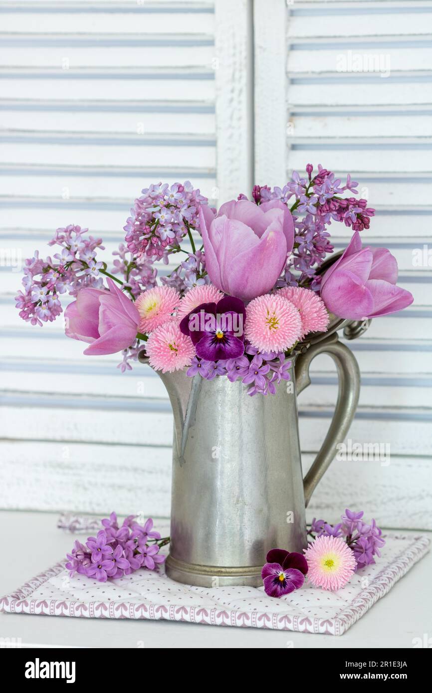 bouquet di fiore di viola rosa, perennis di bellis, tulipani e lilla in lattina di caffè d'annata Foto Stock