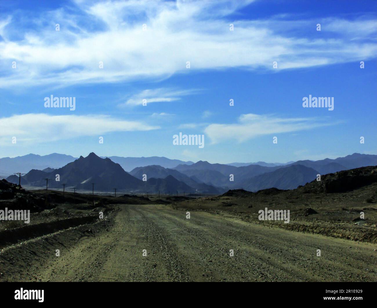 Una strada sterrata deserta che conduce verso le lontane montagne blu del Parco Nazionale di Richtersveld in Sud Africa Foto Stock