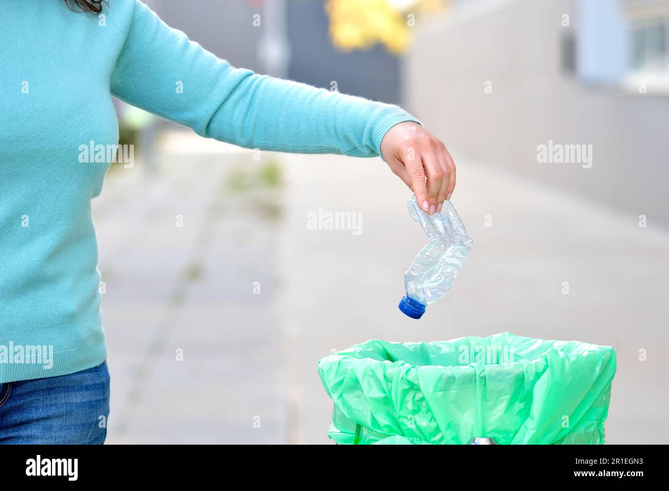 Civic donna gettando spazzatura in un cestino una città Foto Stock