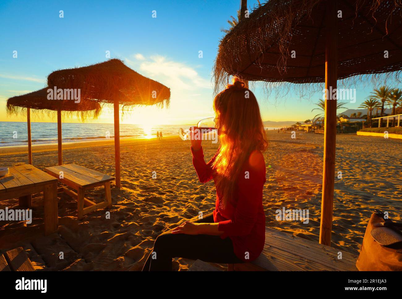 Felice donna asiatica bere vino rosso e guardare il tramonto sulla spiaggia, concetto di celebrazione Foto Stock