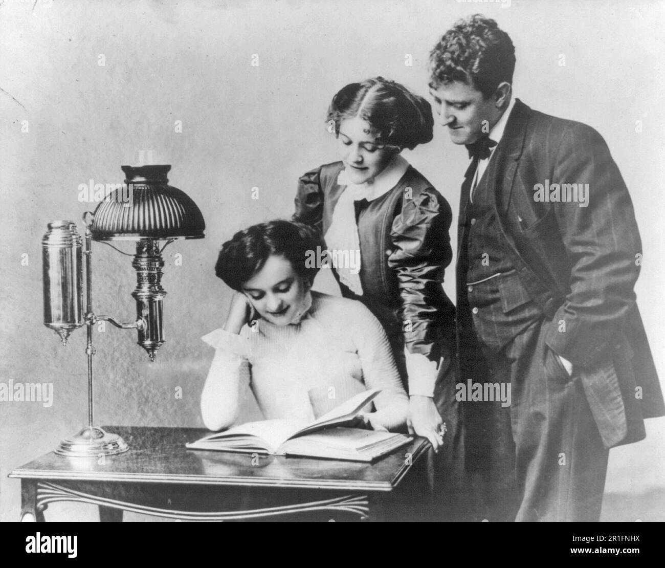 Foto d'archivio: Giovani donne e giovani che leggono alla luce di una lampada brevettata ca. 1909-1932 Foto Stock