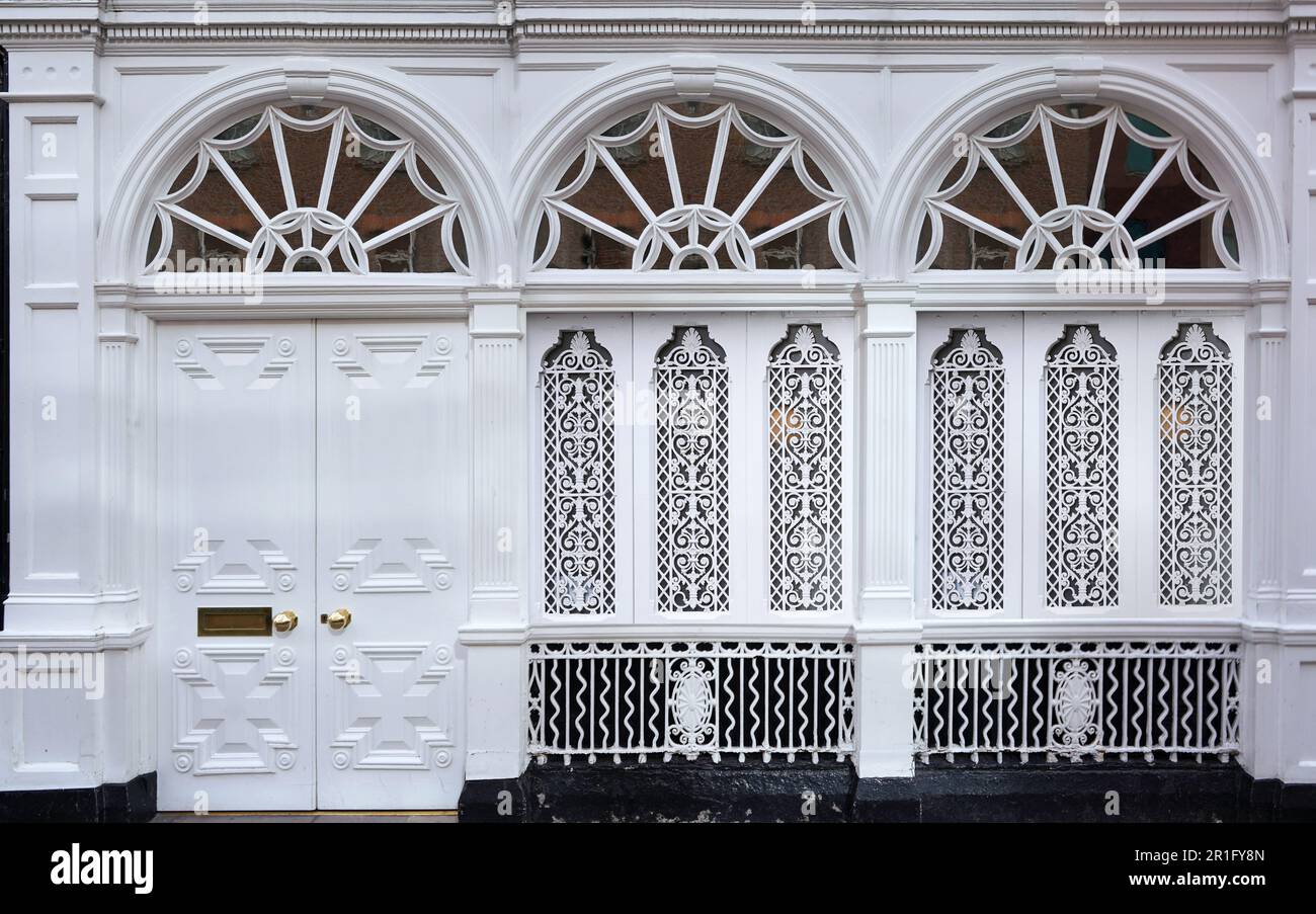Facciata dell'edificio dipinta di bianco, con finestre a ventaglio e griglia decorata Foto Stock