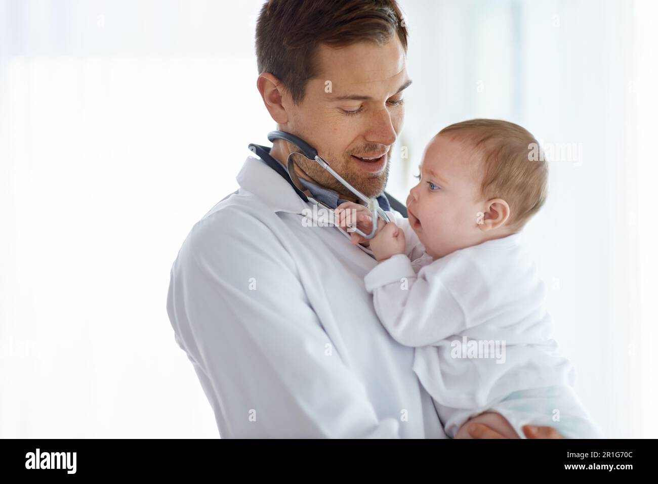 Uomo, pediatra e bambino che gioca con stetoscopio per la valutazione medica, il sostegno o la salute dei bambini. Cute neonato, medico e pediatria dentro Foto Stock