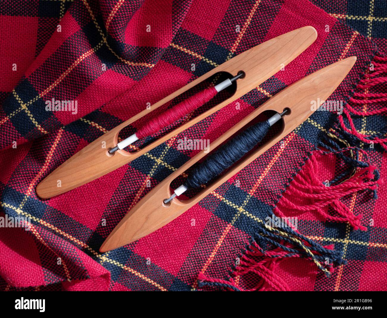 Sciarpa intrecciata con frange e due navette con filo rosso e nero. Produzione tessile. Progetto di tessitura Foto Stock
