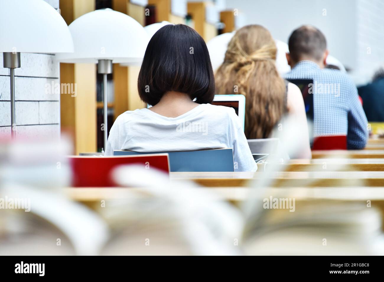 Gli studenti della lettura in una biblioteca pubblica Foto Stock