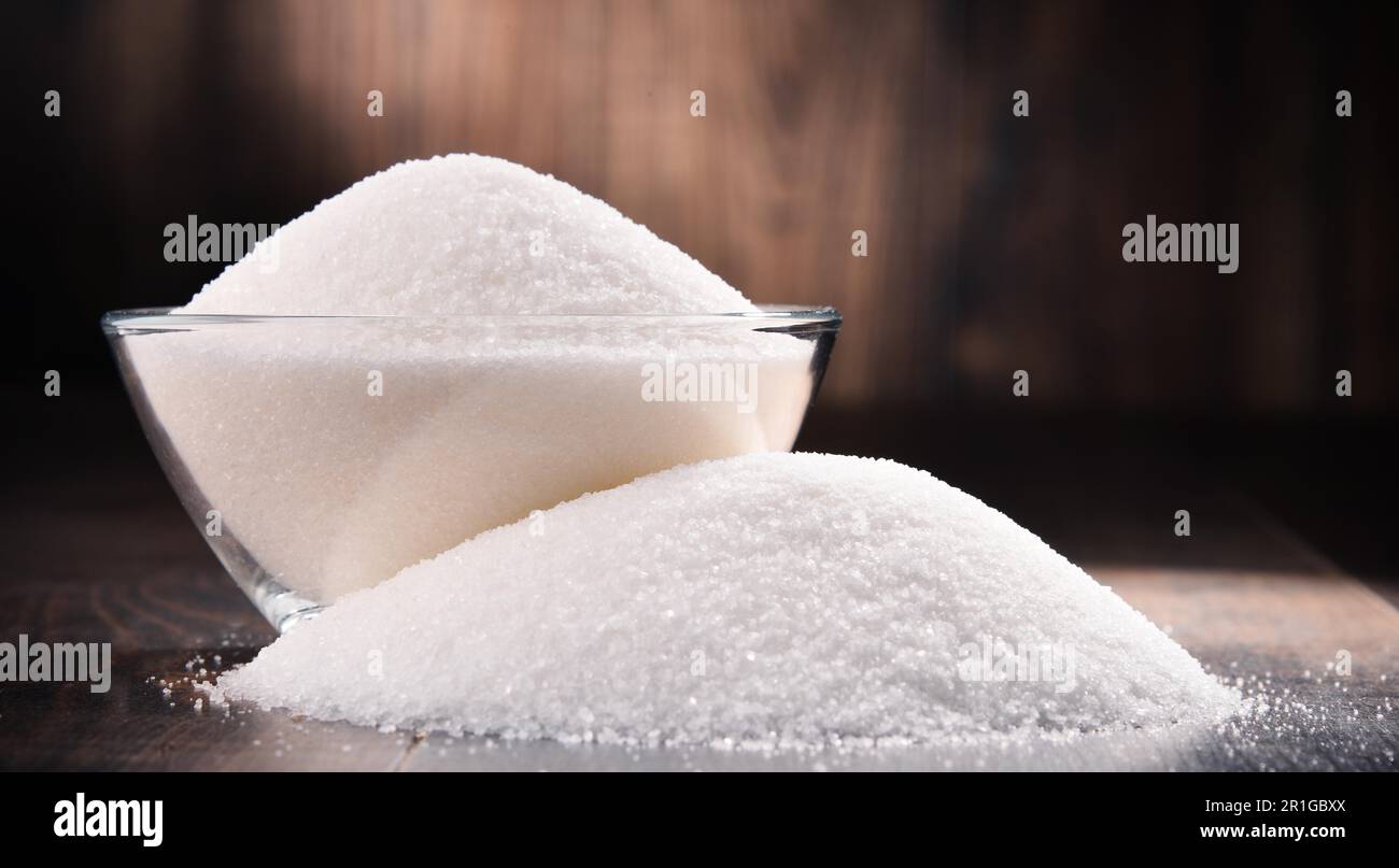 Composizione con ciotola di zucchero bianco raffinato su tavola di legno Foto Stock