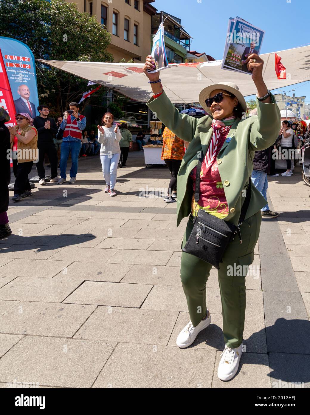 Istanbul, Turchia - Maggio 13 2023: Donna danzante che tiene opuscoli elettorali di fronte al chiosco del Partito popolare Repubblicano nel quartiere di Ortakoy durante le elezioni del 2023 Foto Stock