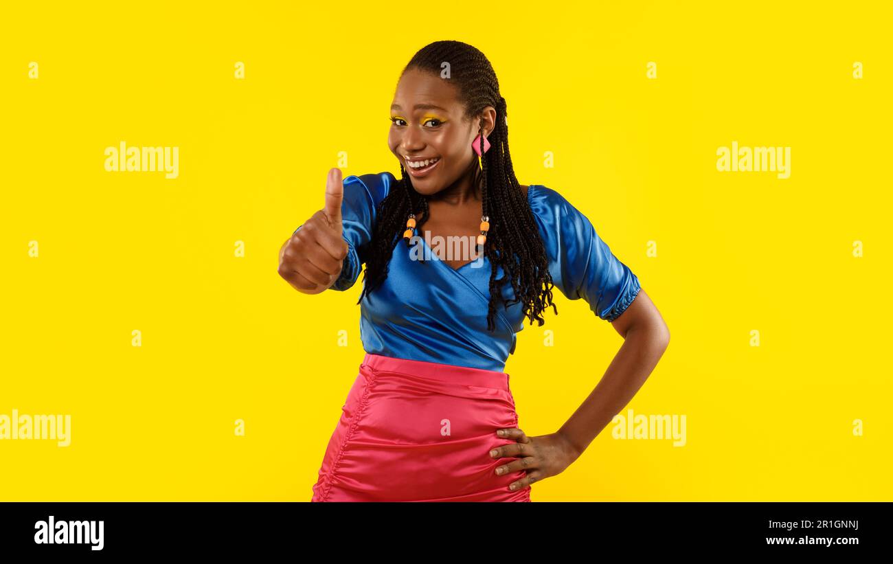 Donna Africana gesturing Thumbs Up in approvazione su sfondo giallo Foto Stock