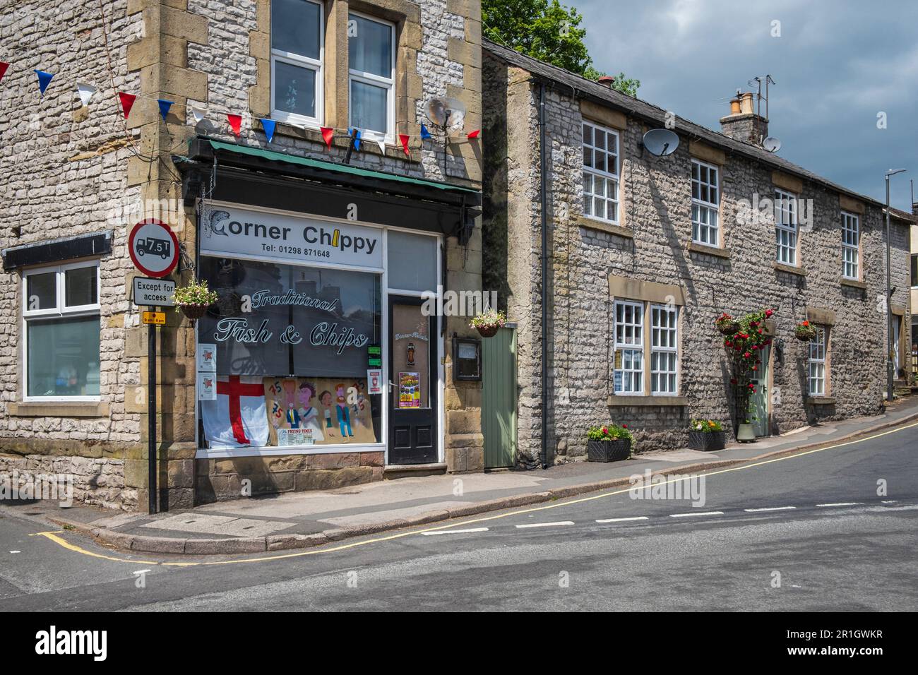 Il negozio Corner Chippy Fish and chip con una vetrina che segna il 75th° anniversario di VE Day, Tideswell, Peak District National Park, Derbyshire Foto Stock