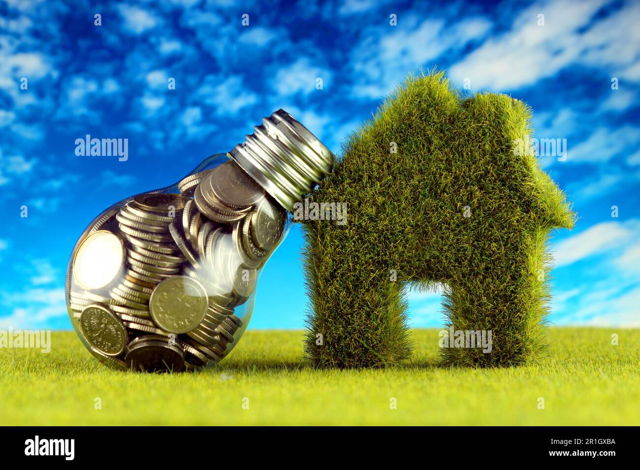 Monete all'interno della lampadina e casa in miniatura con erba. Eco-verde energia rinnovabile concetto. I prezzi dell'elettricità, il risparmio energetico in famiglia. Foto Stock
