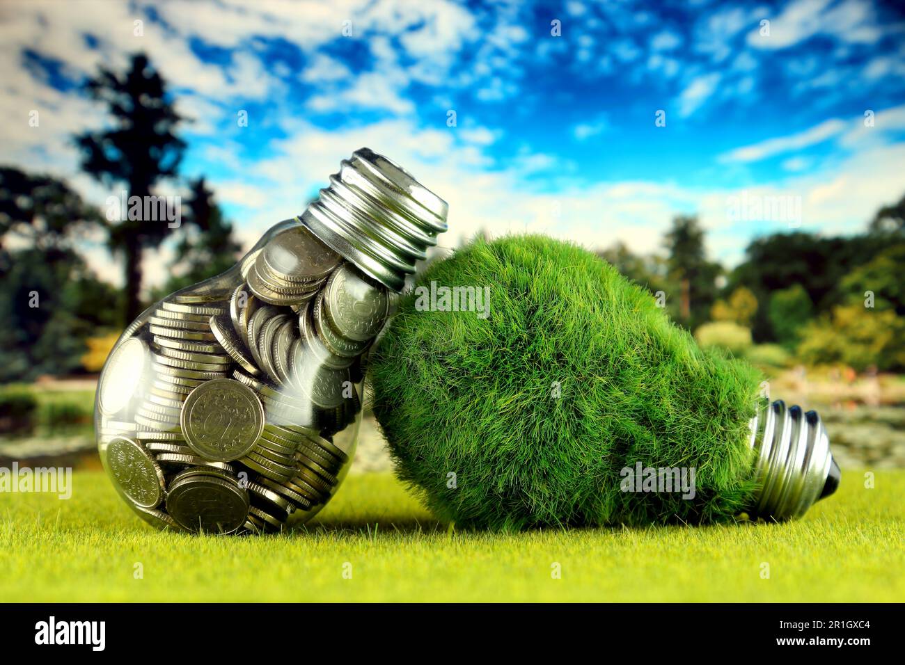 Monete all'interno della lampadina e lampadina verde eco con erba. Concetto di energia rinnovabile. I prezzi dell'elettricità, il risparmio energetico in famiglia. Foto Stock