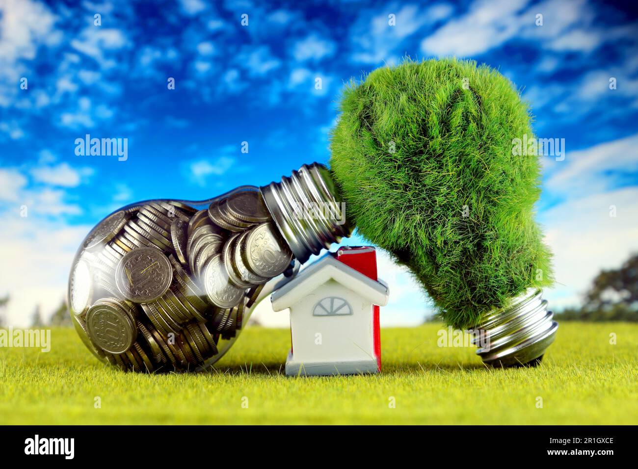 Monete all'interno della lampadina, lampadina verde eco con erba e casa in miniatura. Concetto di energia rinnovabile. I prezzi dell'elettricità, il risparmio energetico nelle ore Foto Stock