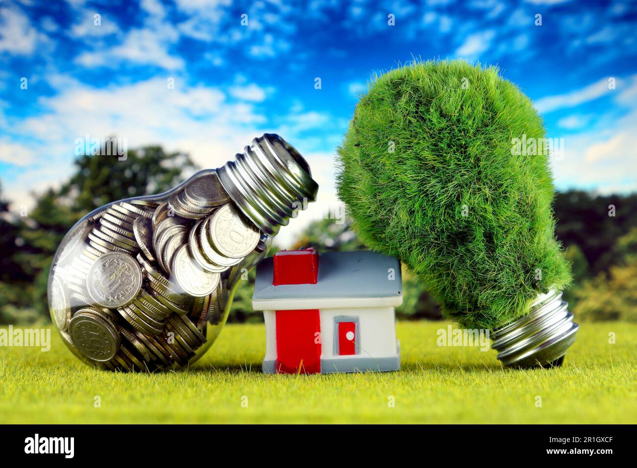 Monete all'interno della lampadina, lampadina verde eco con erba e casa in miniatura. Concetto di energia rinnovabile. I prezzi dell'elettricità, il risparmio energetico nelle ore Foto Stock