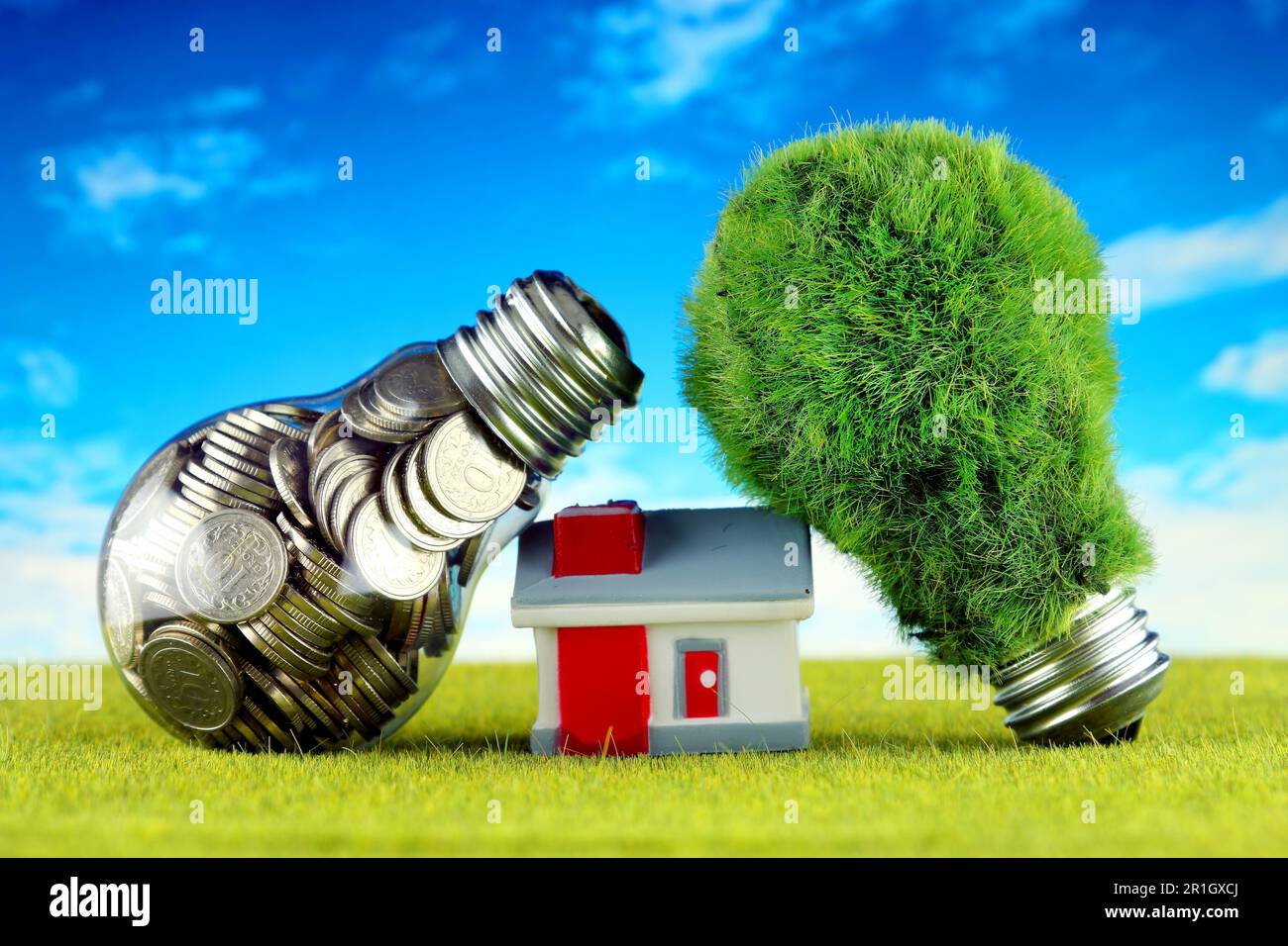 Monete all'interno della lampadina, lampadina verde eco con erba e casa in miniatura. Concetto di energia rinnovabile. I prezzi dell'elettricità, il risparmio energetico nelle ore Foto Stock