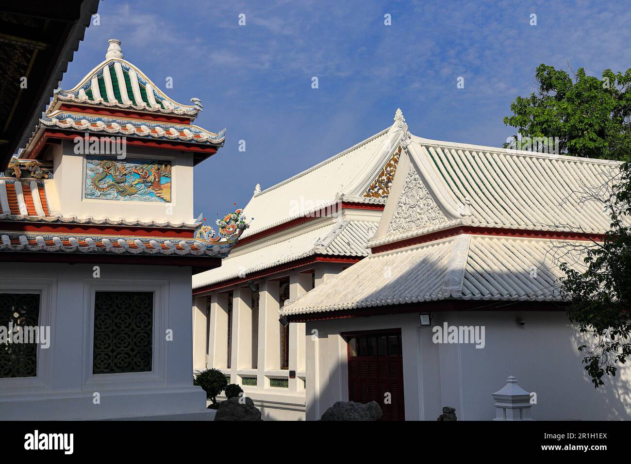 Edificio decorato con bassorilievi di stile Cinese in un tempio tailandese con cielo nuvoloso. Foto Stock