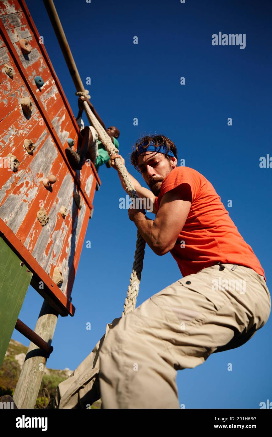 Perseverare e conquistare. un giovane che si arrampica su un ostacolo al bootcamp militare. Foto Stock