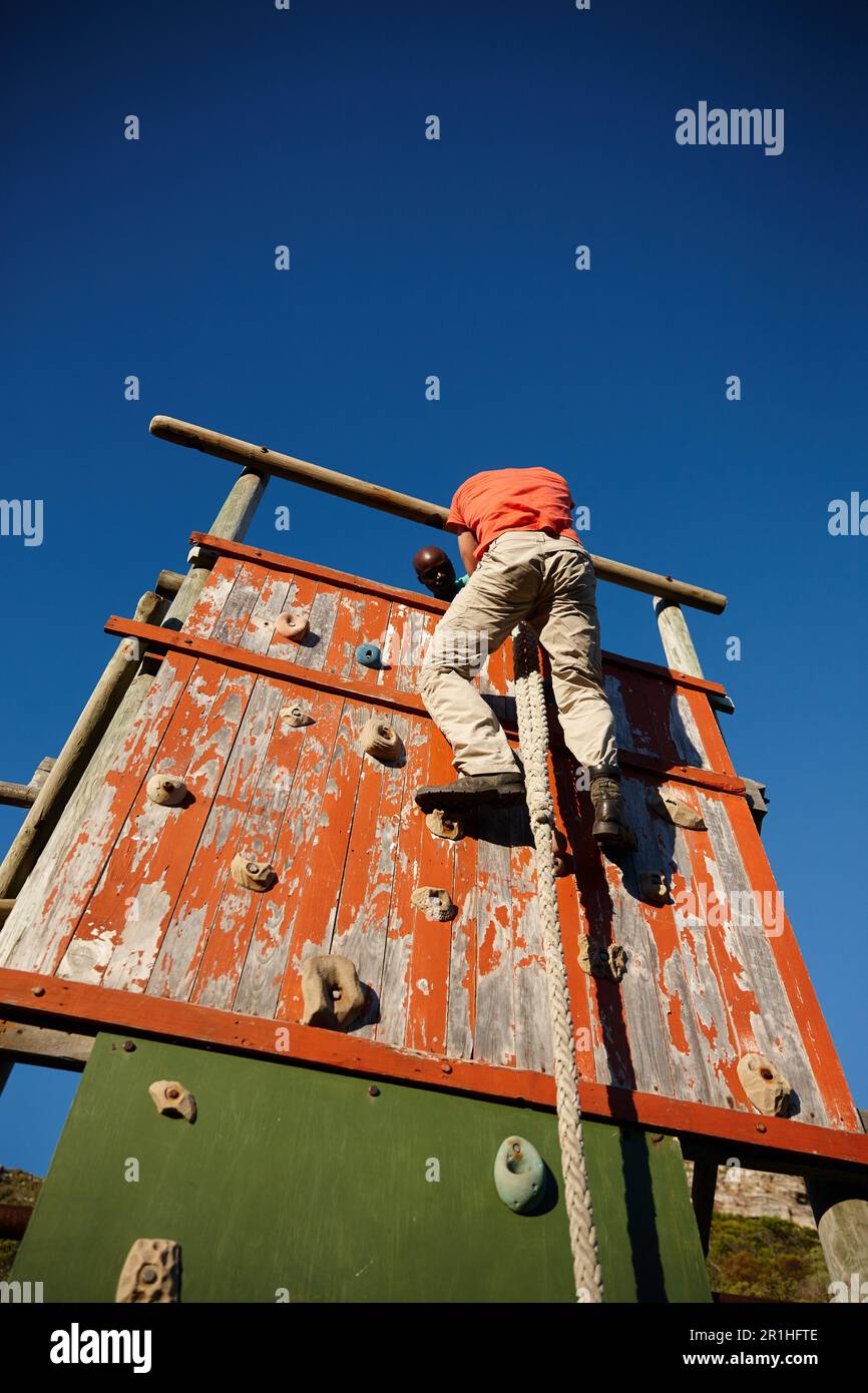 Spingersi verso nuovi livelli di allenamento. un giovane che si arrampica su un ostacolo al bootcamp militare. Foto Stock