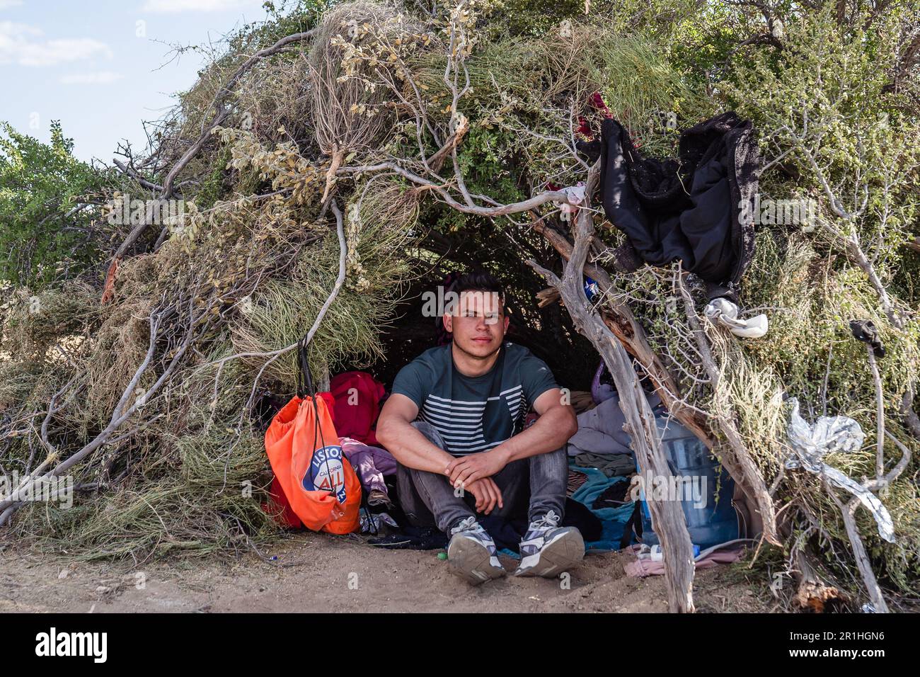Jacumba, Stati Uniti. 13th maggio, 2023. Un giovane migrante della Colombia siede di fronte alla sua tenda di fortuna vicino al muro di confine a Jacumba, California, sabato 13 maggio 2023. Sei persone sono rimaste nella tenda e lui è rimasto dietro per guardare i loro effetti personali, mentre i membri della famiglia e gli amici aspettavano in fila per cibo, acqua e altre donazioni. Il campo per migranti al confine tra Stati Uniti e Messico si trova a circa 60 km da San Diego. Foto di Ariana Dreshler/UPI Credit: UPI/Alamy Live News Foto Stock