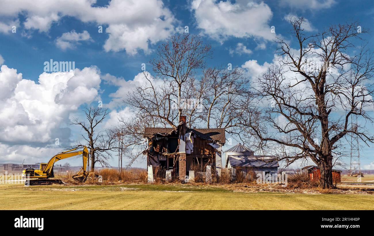 Paesaggio con una vecchia casa che viene demolita con un retroescavatore Foto Stock