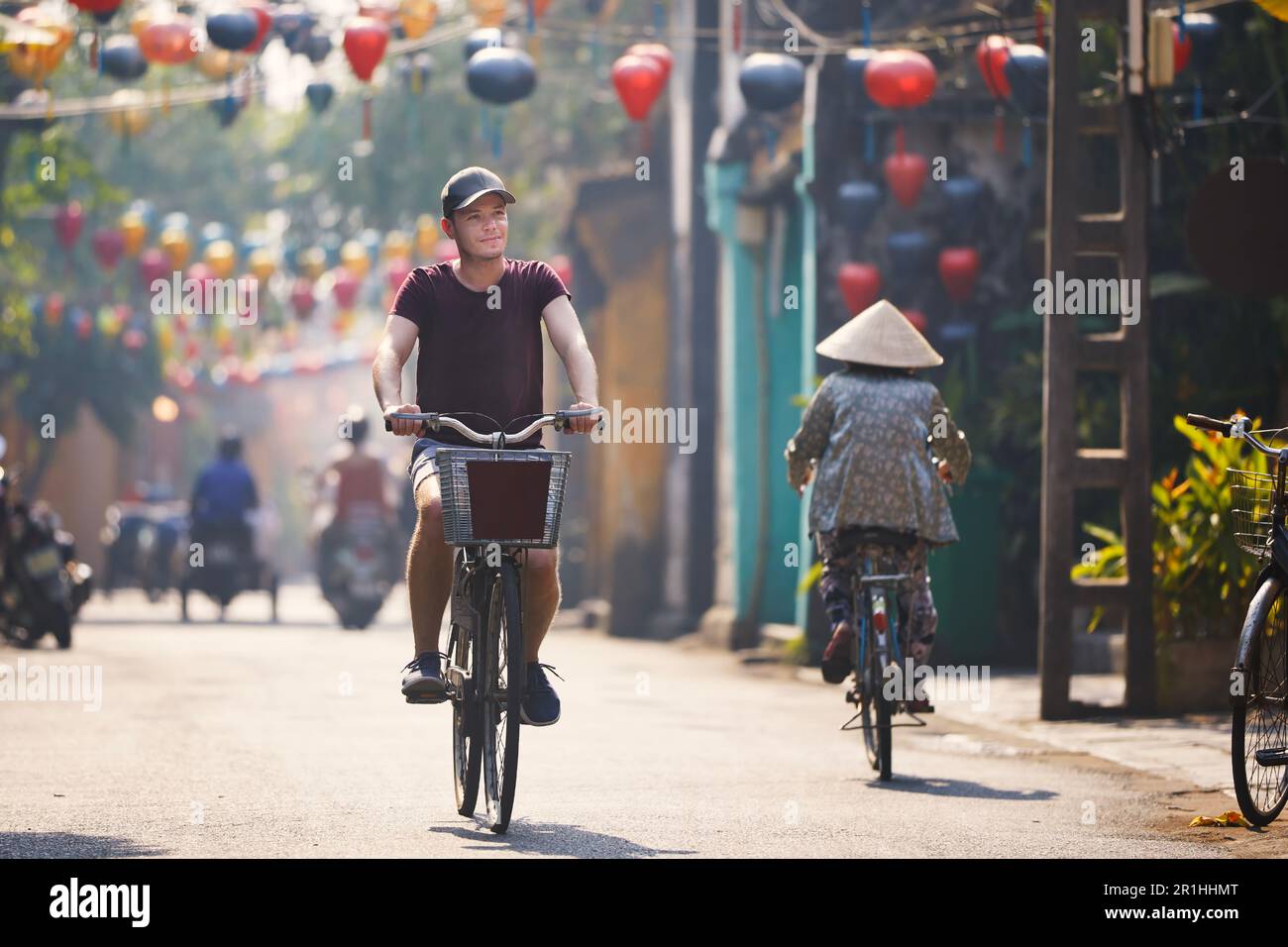 Escursioni in bicicletta nel centro storico. Strada della città antica decorata con lanterne tradizionali, Hoi An, Vietnam. Foto Stock
