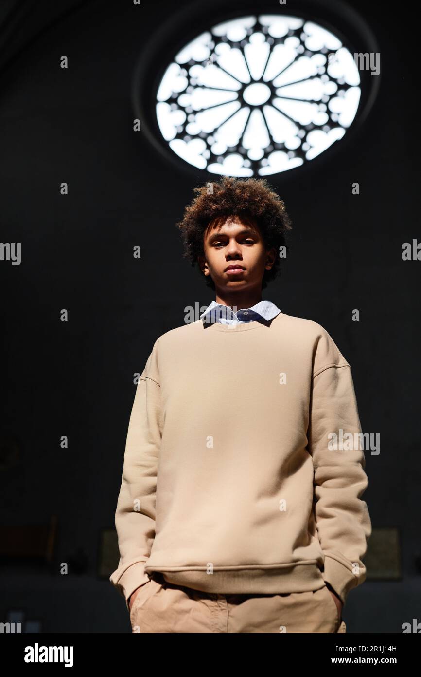 Immagine verticale del ragazzo afro-americano che guarda la telecamera mentre si trova in piedi nella chiesa battista Foto Stock
