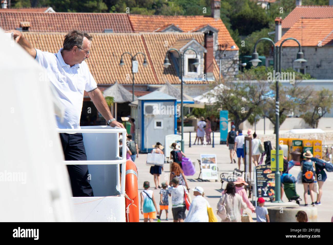 Isola di Zlarin, Croazia - 22 luglio 2022: Persone che lasciano il molo, e un uomo che lavora su un traghetto Jadrolinija guardare dal ponte Foto Stock