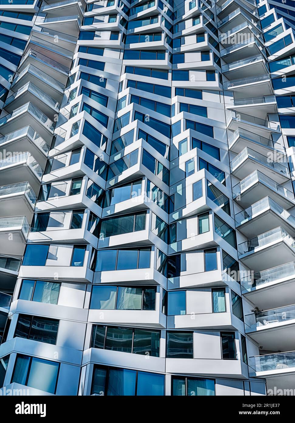 La luce del sole mette in risalto il contrasto tra la luce e le ombre all'esterno di un moderno edificio di appartamenti. Foto Stock